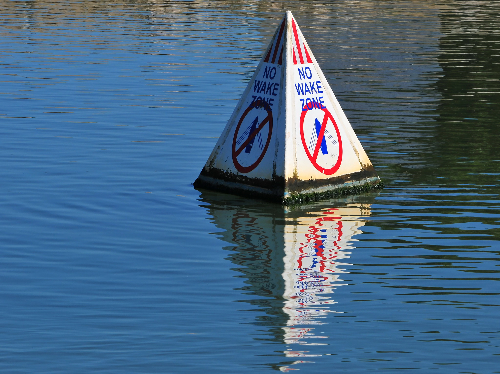 No wake zone sign floating on the water.