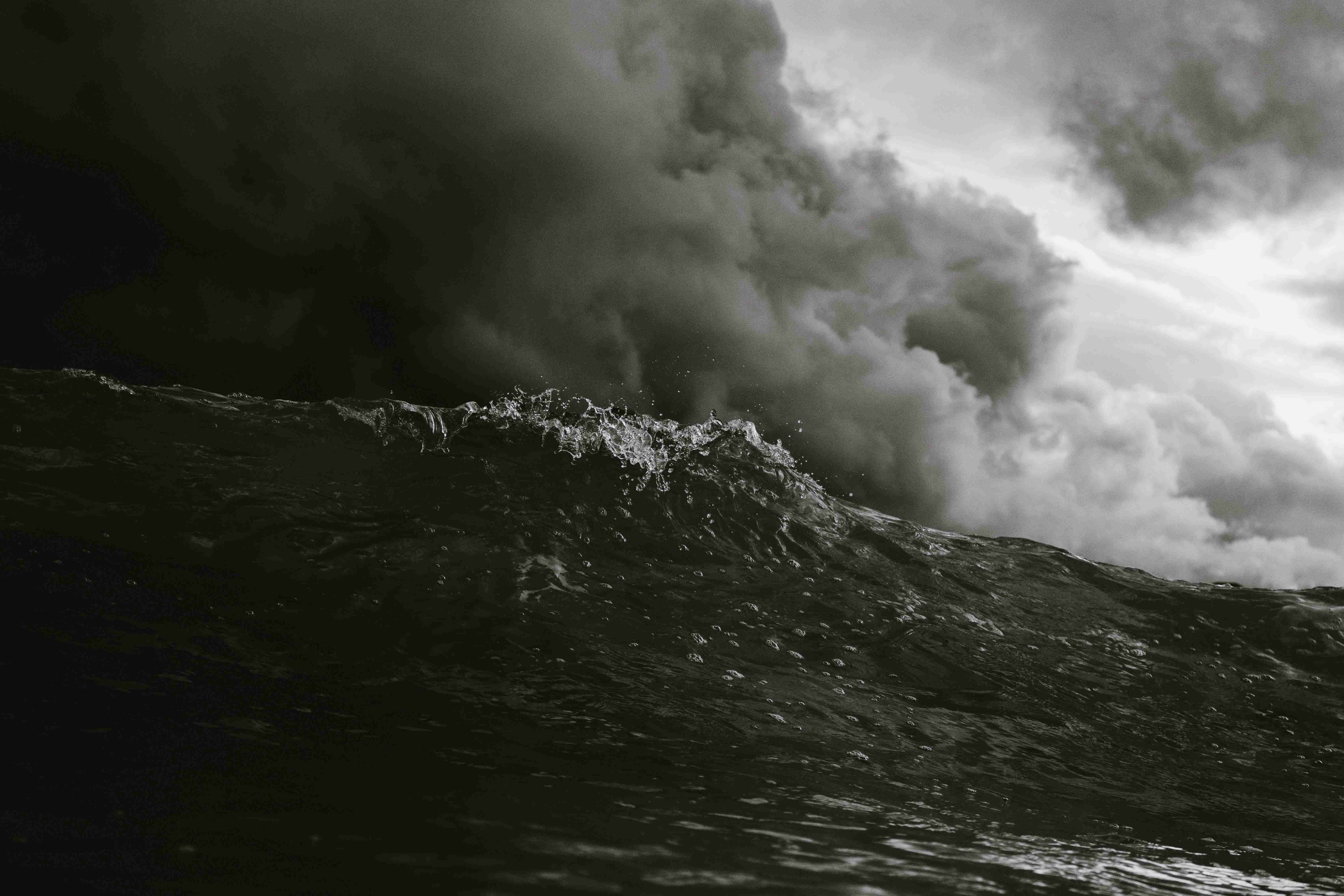 A black and white photo of a large wave in the ocean.