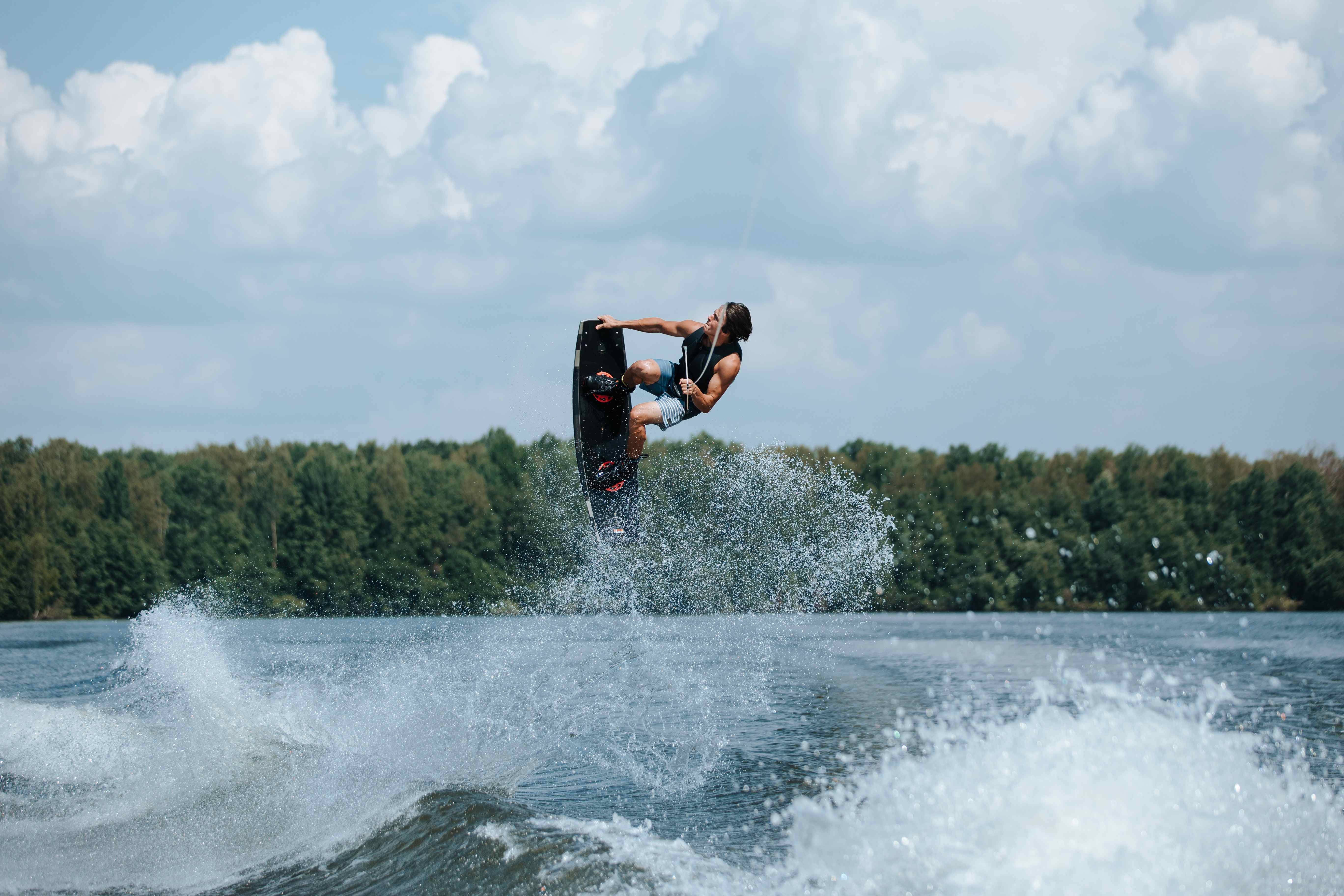 A man doing wakeboarding tricks on a lake.