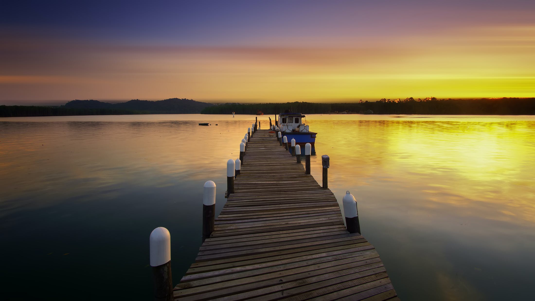 A boat dock on a calm lake at sunset.