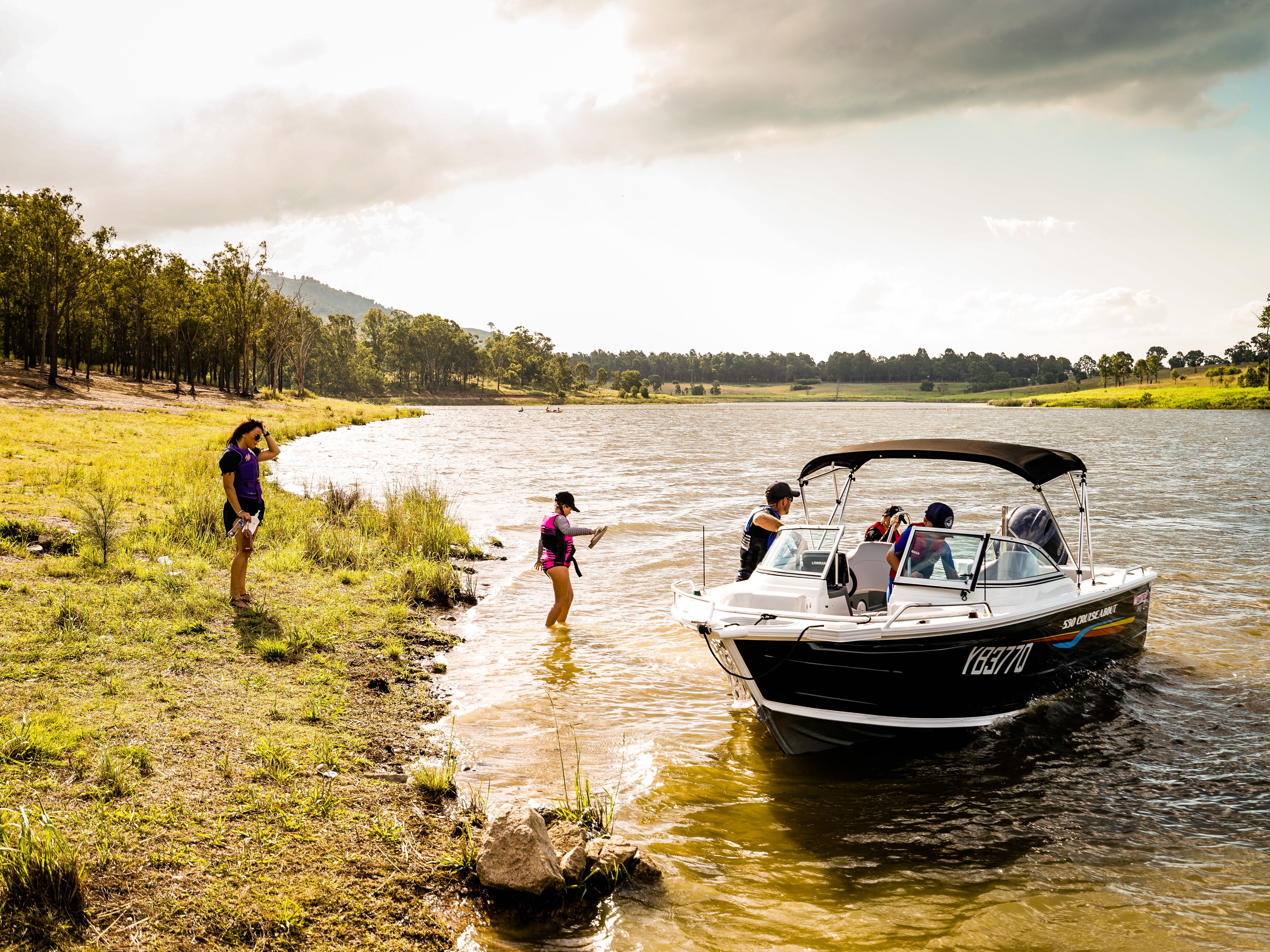 a family on a small beach with a quintrex boat moored on the shore