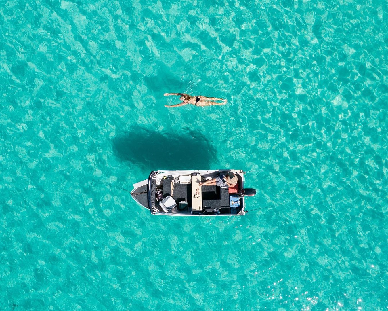 person swimming beside a quintrex tinny