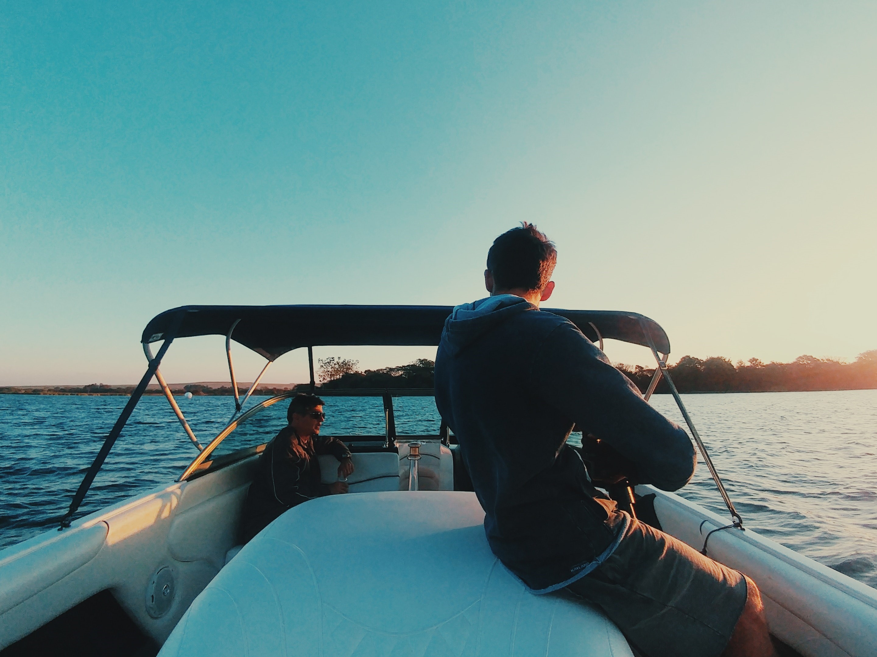 Two people onboard a boat with a Bimini top.