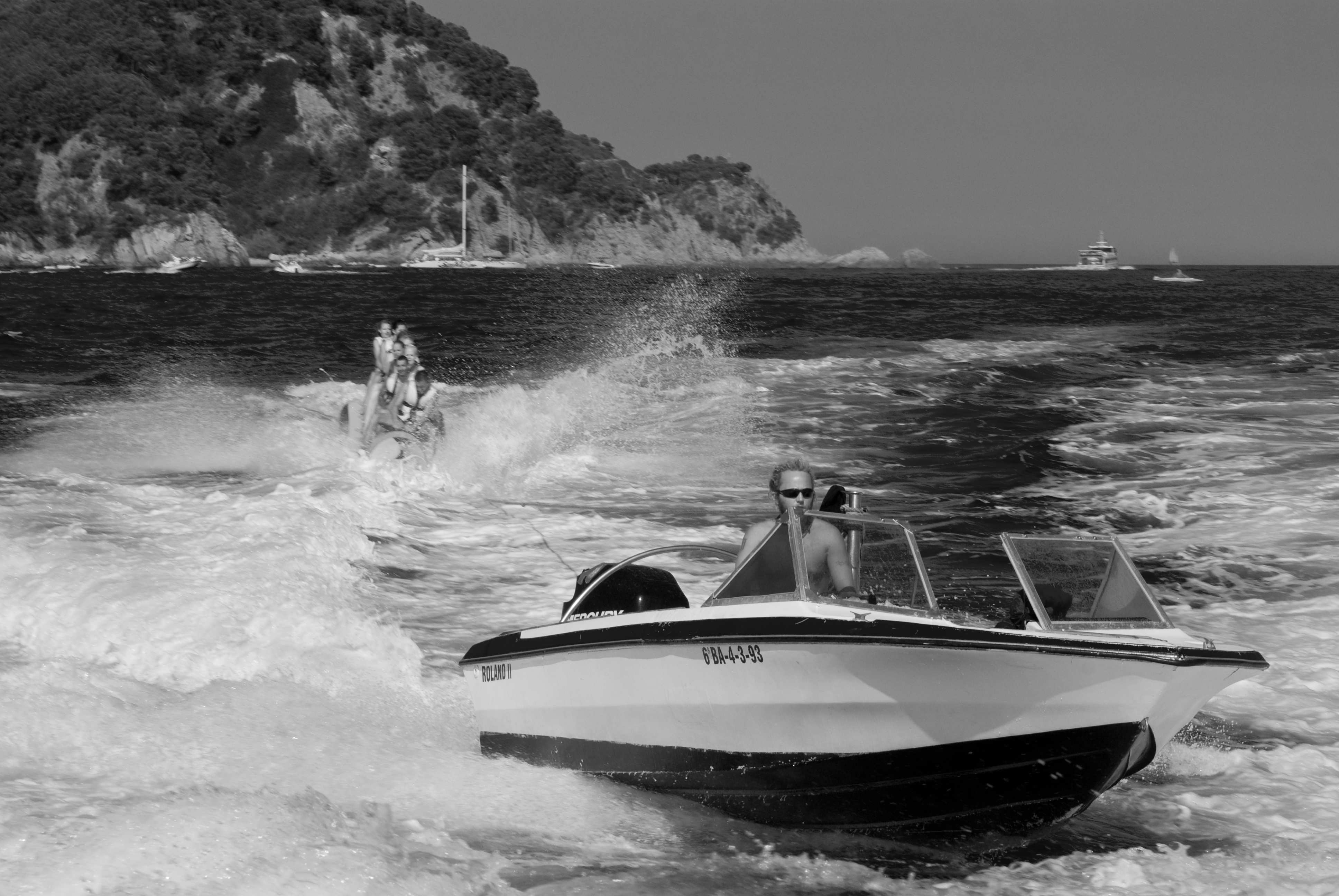 A black and white photo of a boat towing a tube.