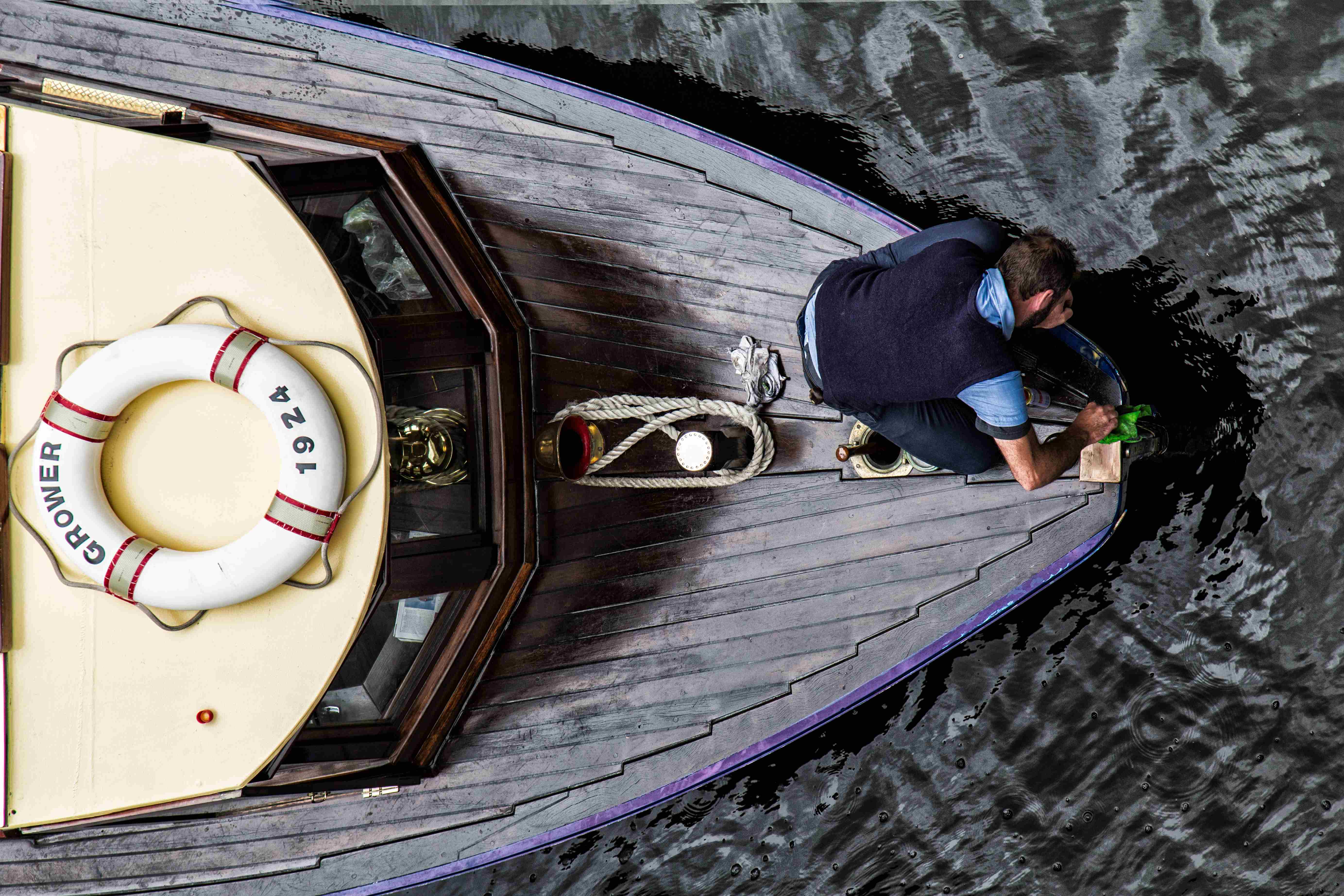 A man cleaning the bow of a wooden boat.